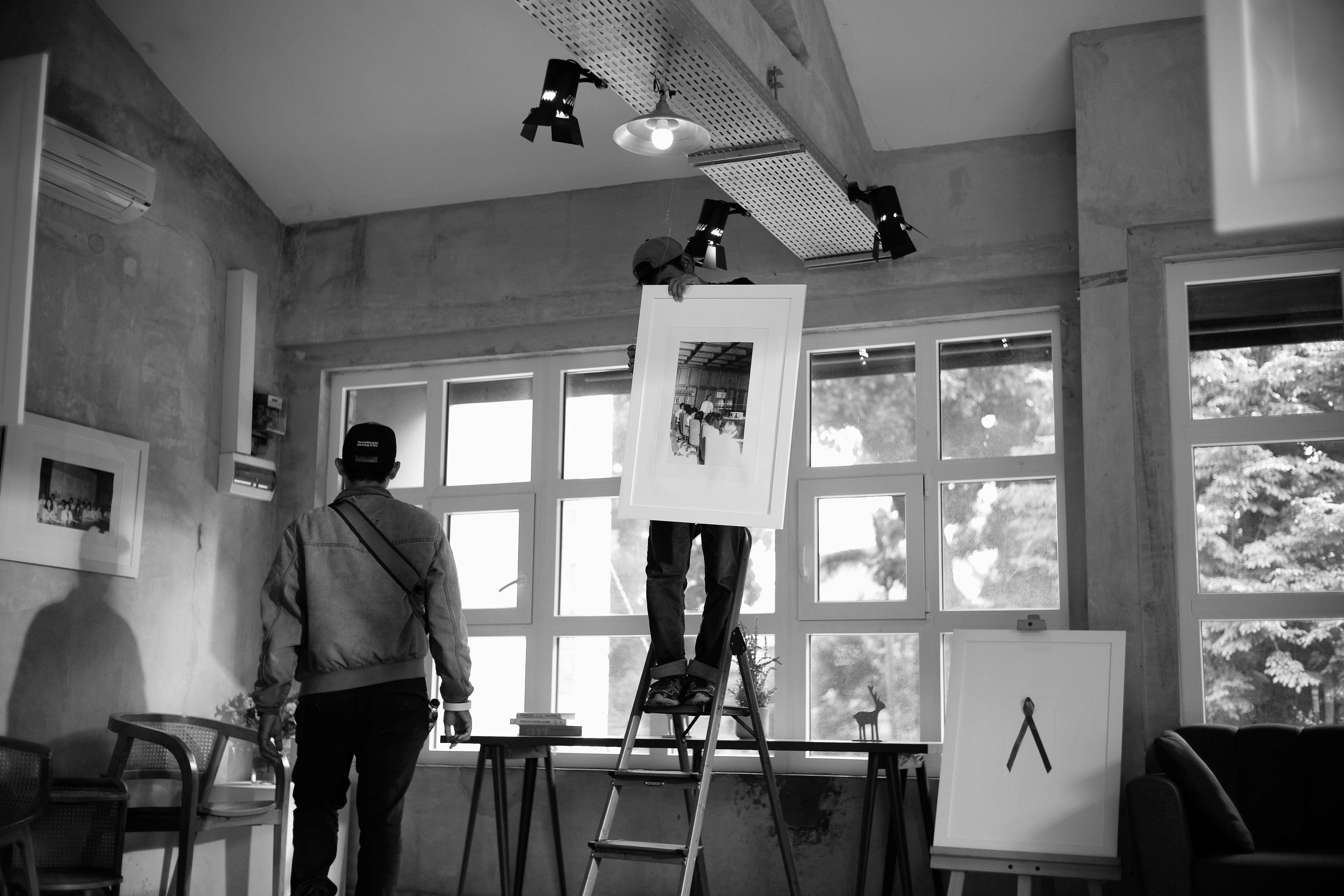Gallery workers carefully hang intricate tufted artworks, preparing an exhibition showcasing textile