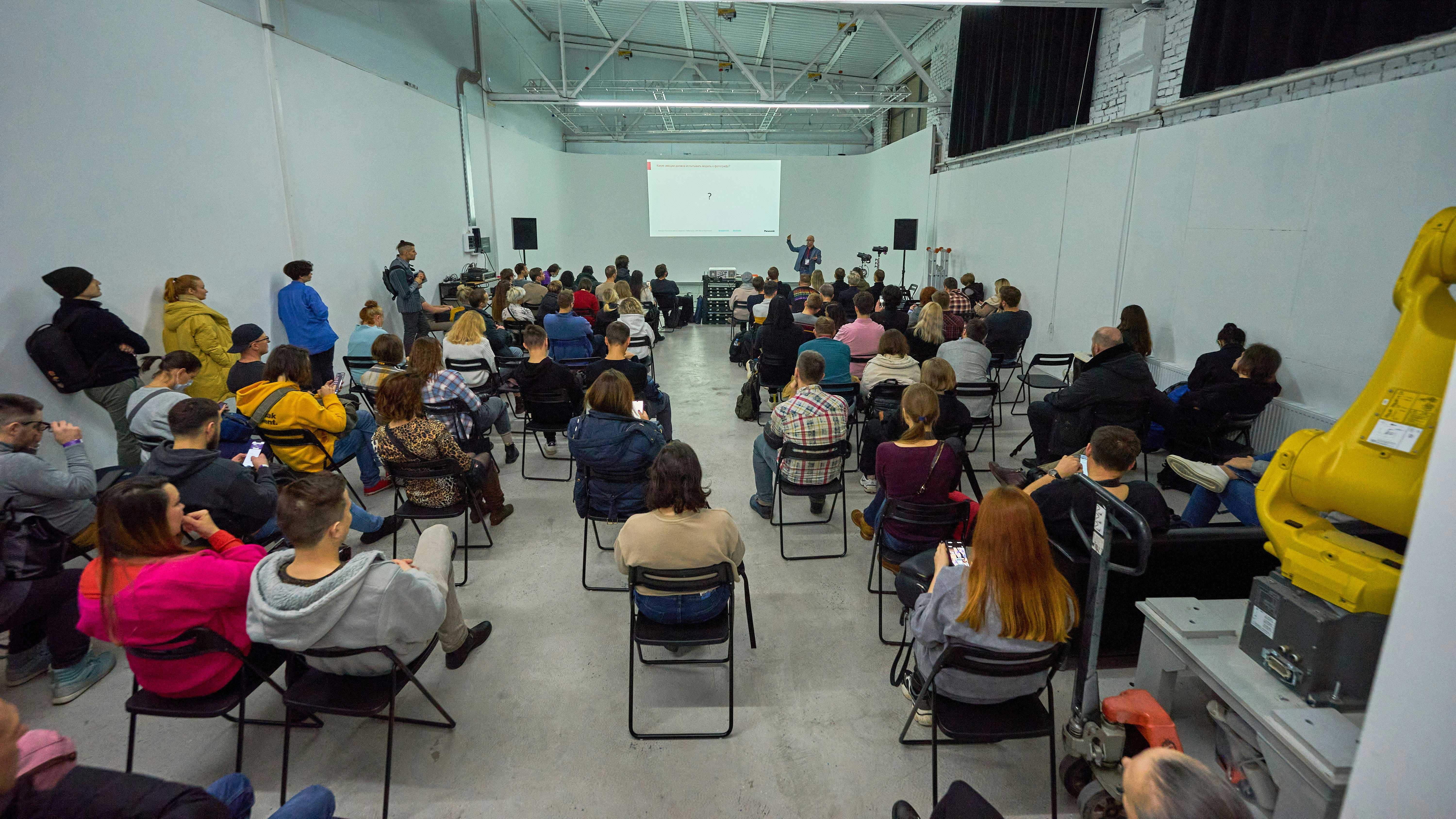 Workshop participants seated in rows, attentively listening to the introductory session on tufting